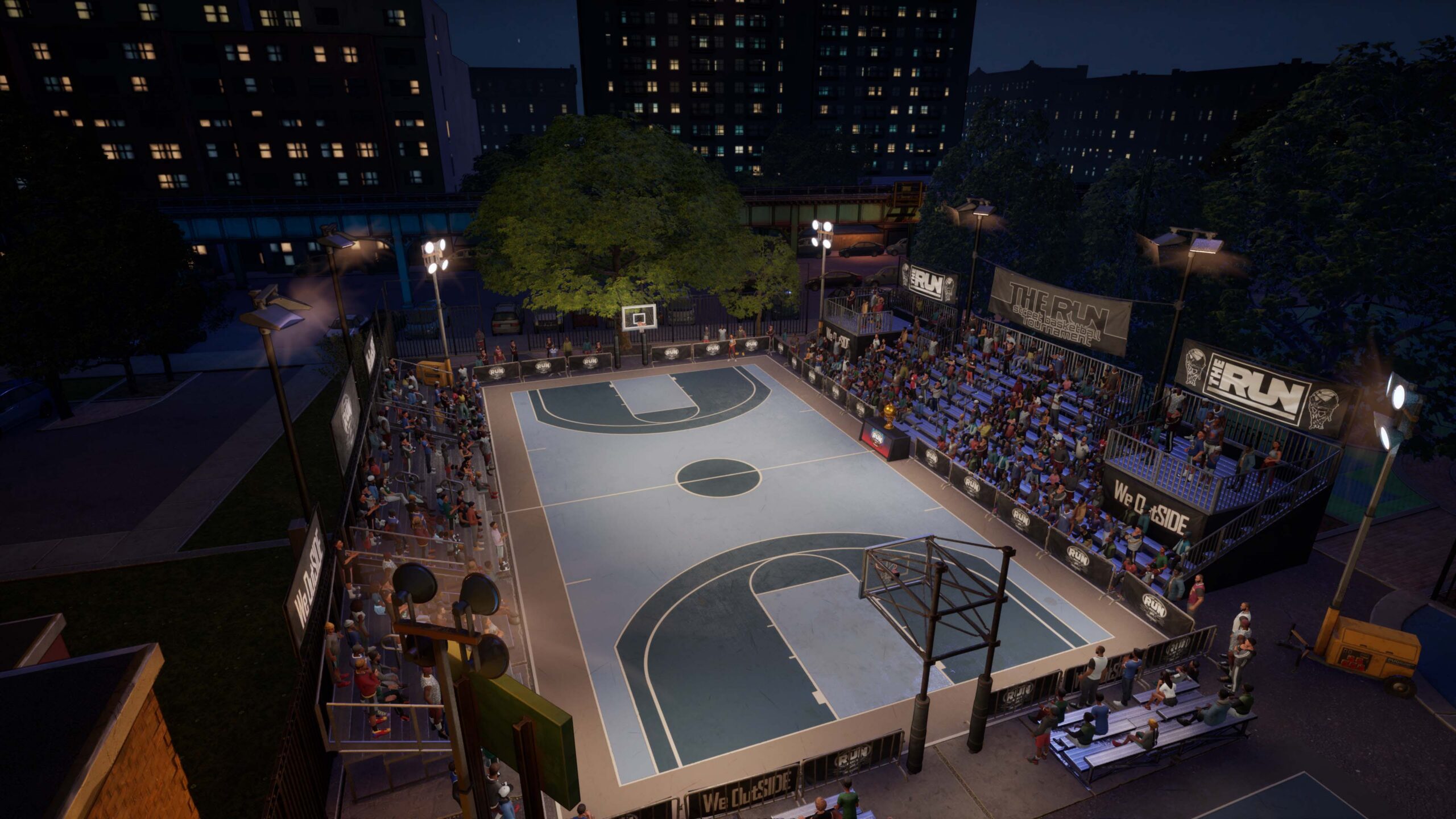 An outdoor basketball court at night, surrounded by stands and apartment blocks, in NBA The Run