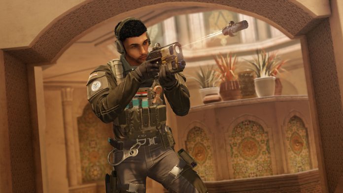 An operator aims a pistol through an archway in a Rainbow Six Siege screenshot