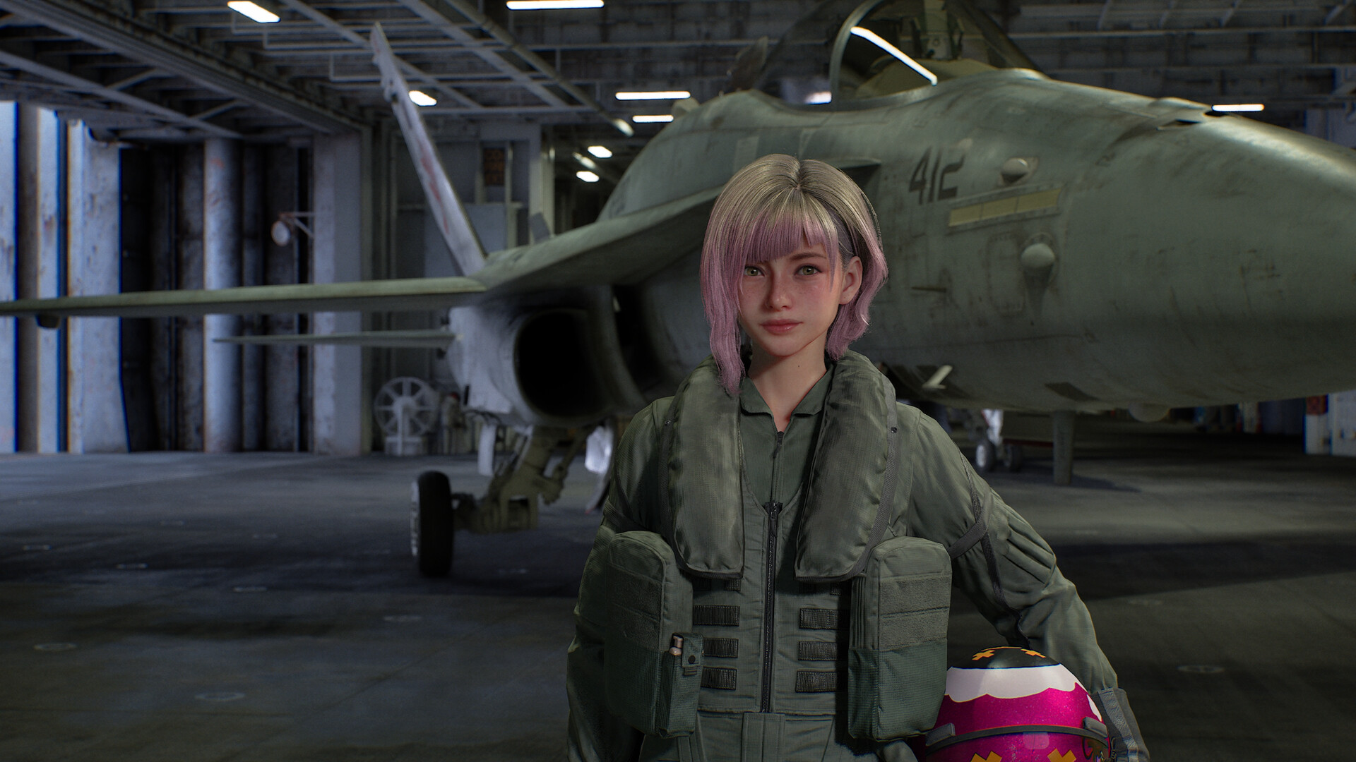 A pilot in a flight suit stands in a hangar in front of a grey fighter jet