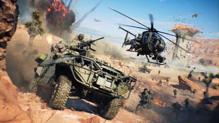 An armoured vehicle with a gunner kicks up dust in a desert canyon as a helicopter and jets fly overhead and explosions go off behind.