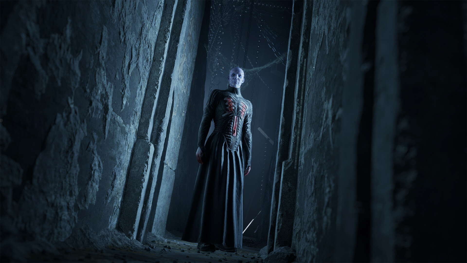 Pinhead stands in a dark stone corridor lit in cold blue