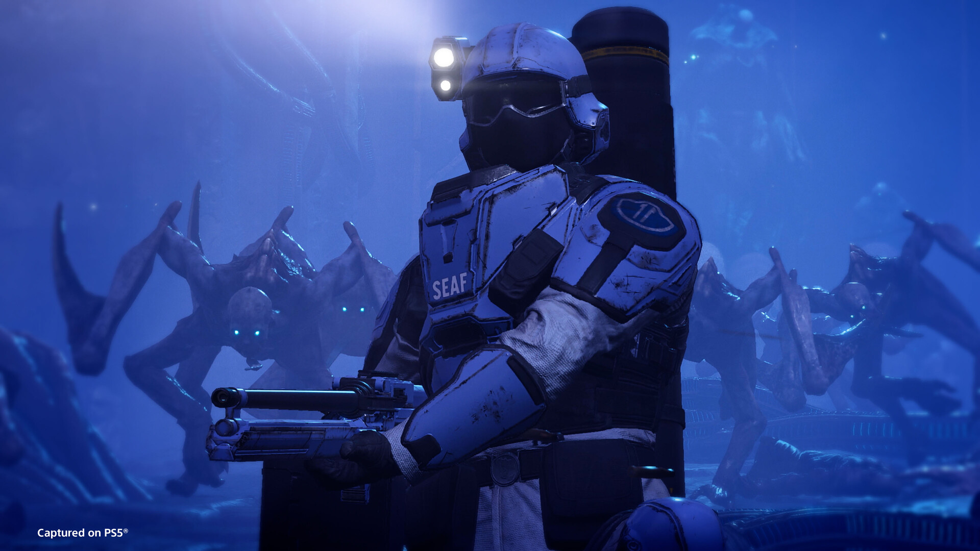 A SEAF soldier with a head torch holds a rifle while spindly alien creatures loom behind in blue light.