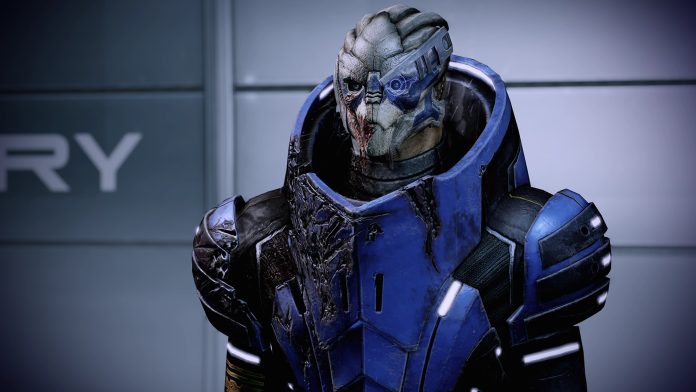 Mass Effect Legendary Edition – Garrus Vakarian screenshot. Image BioWare A Mass Effect Legendary Edition screenshot of Garrus, a turian in battered blue armour with a visor over one eye and blood on his face.