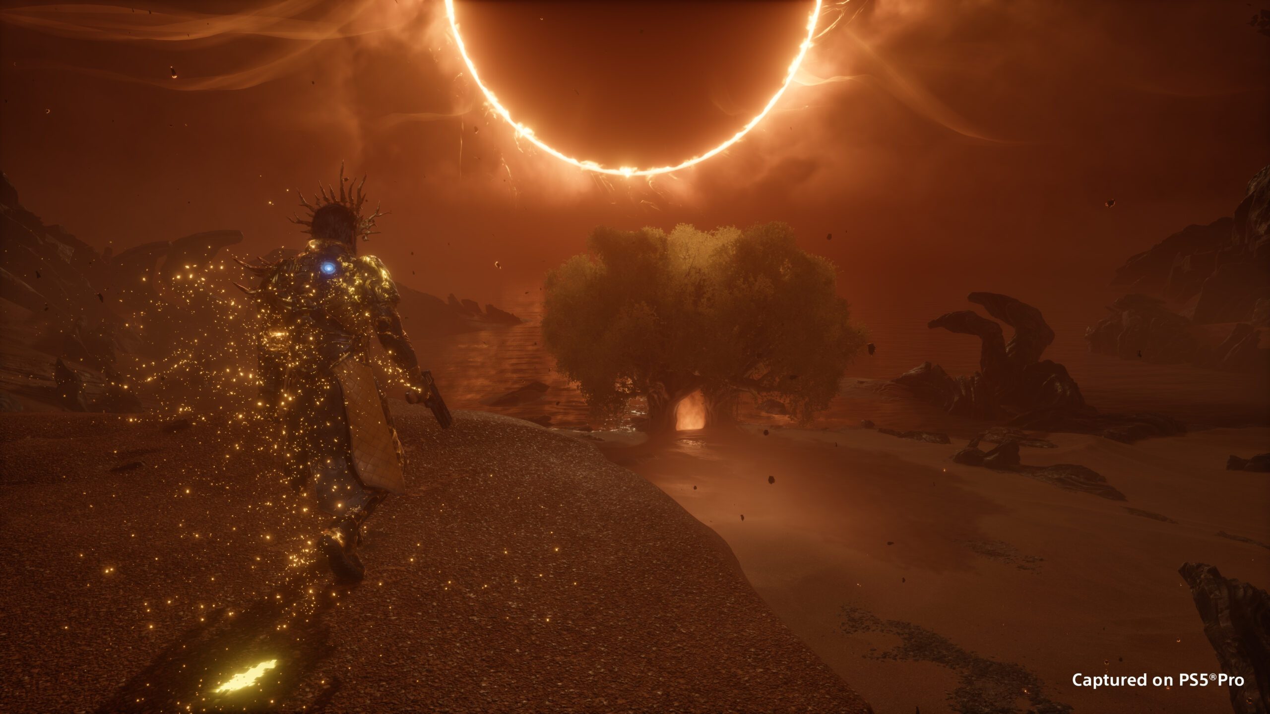 A gold-glowing, crowned armoured figure running across a rust-coloured shore towards a tree beneath a ring-shaped eclipse in Saros