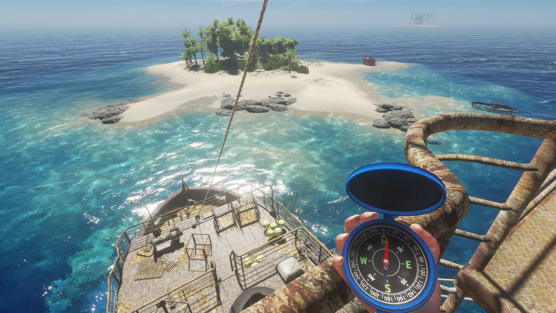 First-person view in Stranded Deep from the rusted deck of a wreck, holding an open blue compass, looking over clear water to a small palm-covered island.