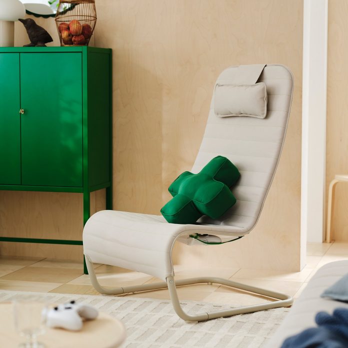 The YXSTABY gaming lounge chair and D-pad cushion. Image: IKEA A beige YXSTABY lounge chair with a green D-pad cushion, beside a green cabinet and an Xbox controller