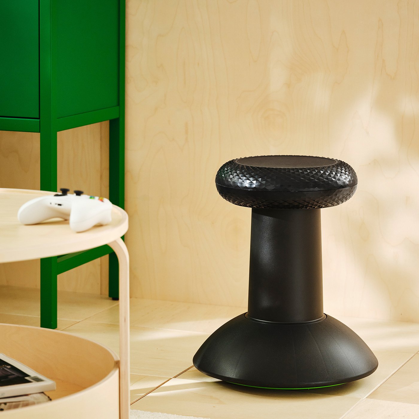 A black stool shaped like an Xbox controller thumbstick, with a textured top, in a living room