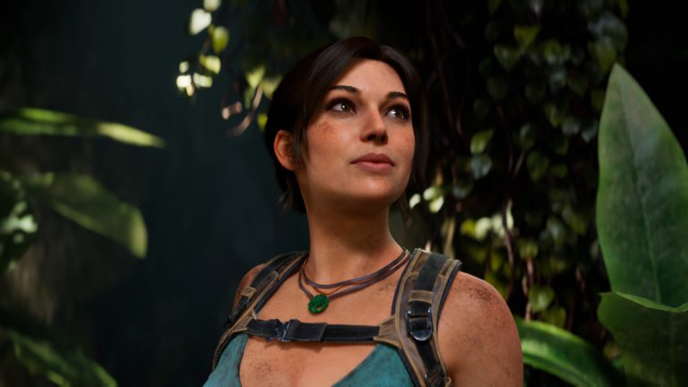 A close-up of Lara Croft in Tomb Raider: Legacy of Atlantis, with short dark hair, a dirt-smudged face, a green pendant and pack straps, looking up in a jungle.